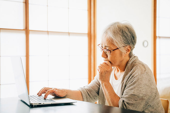 パソコンを前に考えている高齢者
